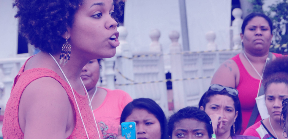 Mulher discursa para plateia feminina durante encontro nacional de mulheres