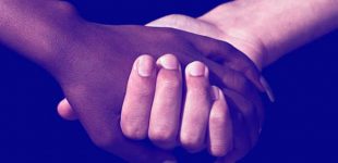 Mãos dadas entre uma pessoa negra e outra branca